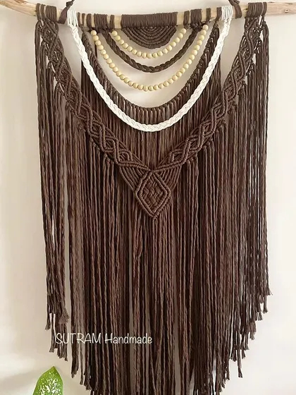 This large tapestry is made with rich chocolate brown cotton and features layers of white and beaded details. The wooden beads add a natural, earthy element to the design.