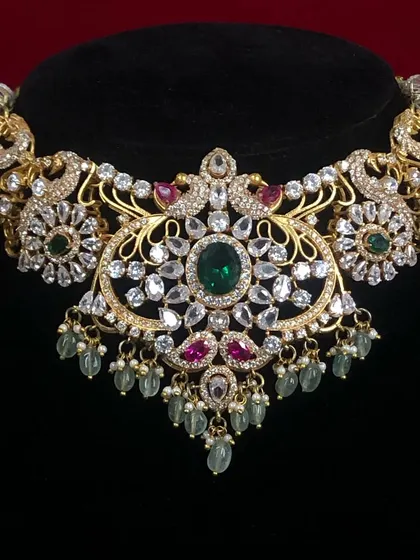 A close-up of a beautiful polki and emerald choker. The intricate design and sparkling stones make this a very luxurious piece.