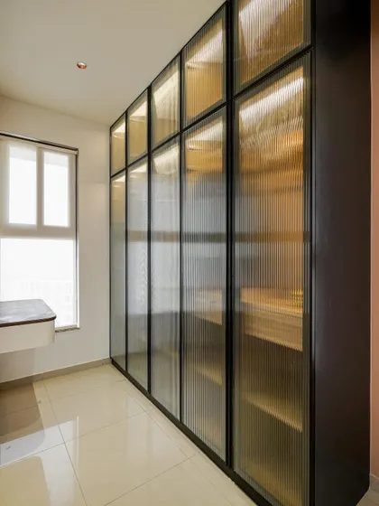 A modern wardrobe with fluted glass panels and internal lighting, offering a sleek storage solution.