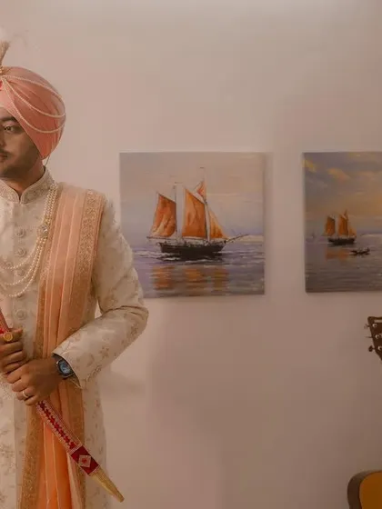 A portrait of the Sikh groom, looking regal in his sherwani and turban, holding the kirpan as he prepares for his wedding.