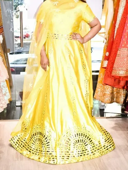 A full-length view of the yellow Anarkali, showing its beautiful flare and cut-work details at the hem.