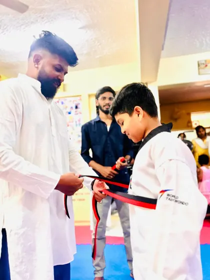 Tying a red and black belt, recognizing advanced skill.