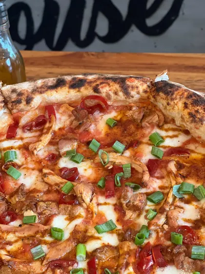 A close-up of the Adobo Chicken pizza, with our logo in the background. It's a signature for a reason.