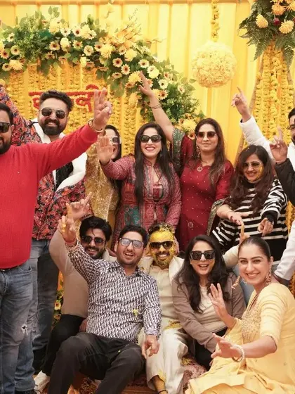 A big group photo capturing the entire family and friend squad celebrating the Haldi ceremony with enthusiasm.