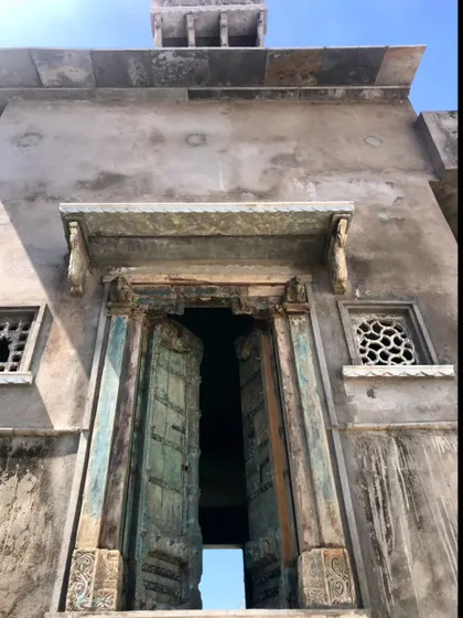 A beautifully aged door with hints of blue paint, set within a grand stone entrance. This image captures the essence of heritage architecture that we seek to honor and reinterpret in our work.