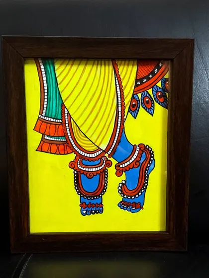 A close up painting of the lotus feet of Krishna, a symbol of devotion and surrender. The details of the anklets and the bright colors make this 9x10 inch framed piece special.