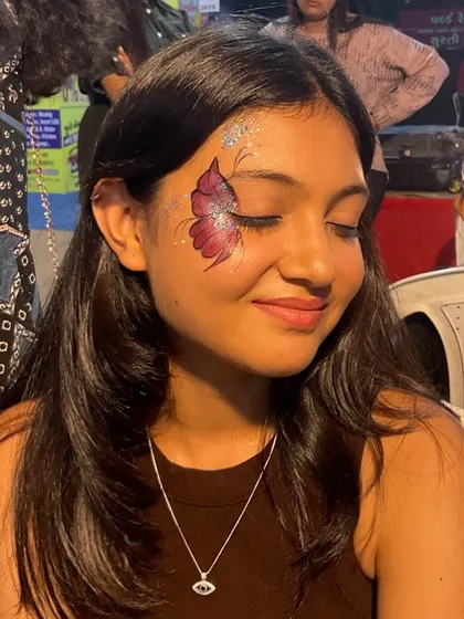 A happy client with her eyes closed, showing off a beautiful pink and red butterfly design.