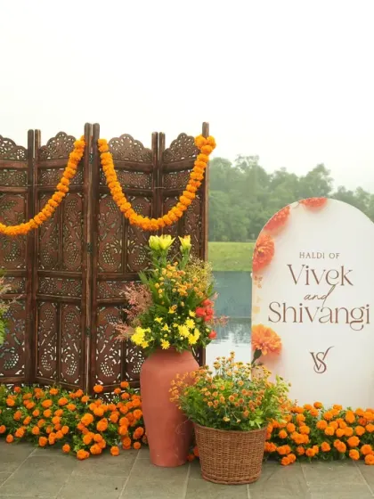 A beautiful photo corner at the Haldi, combining the personalized welcome sign with a traditional wooden screen and vibrant floral arrangements.