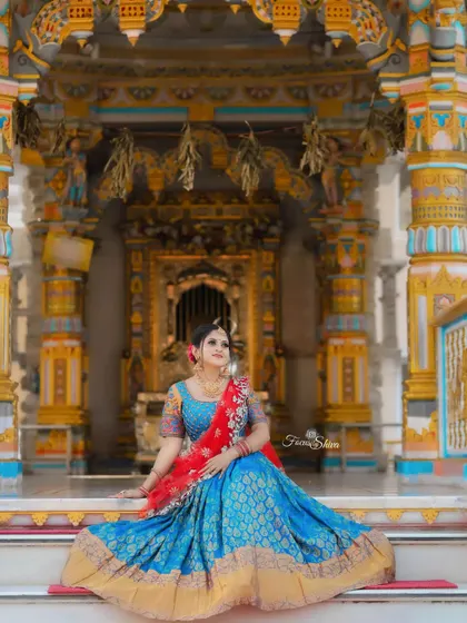 The grandeur of the temple setting perfectly complements this traditional blue and red half saree.