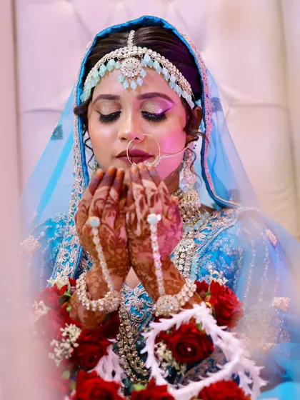 A close-up of the bride's face as she prays, highlighting the delicate details of her matha patti and nose ring.