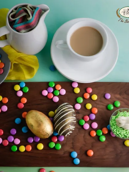 Indulge in our rich, dark chocolate Easter eggs. This image displays our beautifully crafted eggs, including a golden egg and one with a marbled design, surrounded by colorful candies.