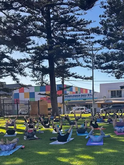 The energy of a large group practicing together is truly powerful. Here, students are holding a core-strengthening pose during our sunny park session.