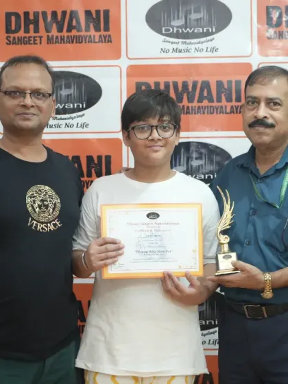 A student receives his trophy and certificate at the Dhwani Kala Mahotsav. Every participant's effort is acknowledged and celebrated on our platform.