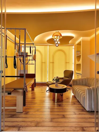 A wider view of the private training room, showcasing the elegant design, ambient lighting, and top of the line Pilates Cadillac. This is where personalized transformation happens.