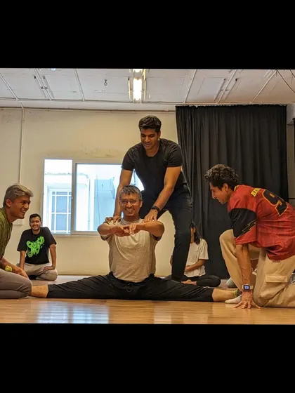 It takes a team to achieve great things. Here, fellow students help a dancer with a full split, showcasing our supportive community.