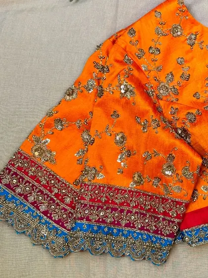 An orange raw silk blouse with hand-embroidered gold zari and zardosi.