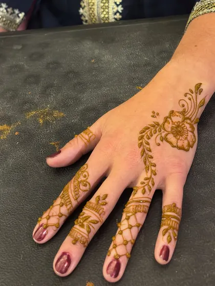 A delicate floral design on the back of the hand for a guest. This is a great option for those who want a visible yet understated mehendi.