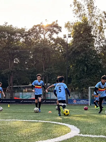 Players practicing dribbling drills in a group. This not only improves individual skill but also fosters a sense of teamwork and friendly competition among the players.