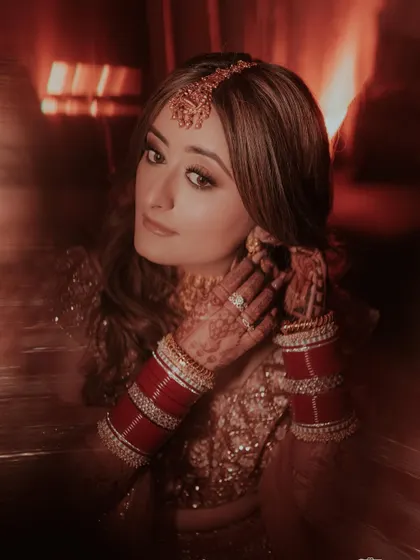 An artistic, motion-blur portrait of the bride as she adjusts her earring, the red tones and soft focus creating a dreamy, romantic feel.