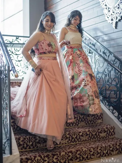 The bride and her sister or bridesmaid descending a grand staircase together. A lovely candid moment showing sisterly love and support.