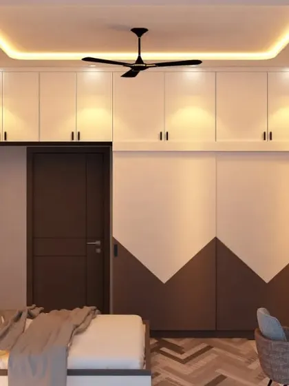 A master bedroom with a striking two-tone sliding wardrobe in white and brown. The geometric design on the wardrobe is complemented by the chevron-patterned wooden flooring.