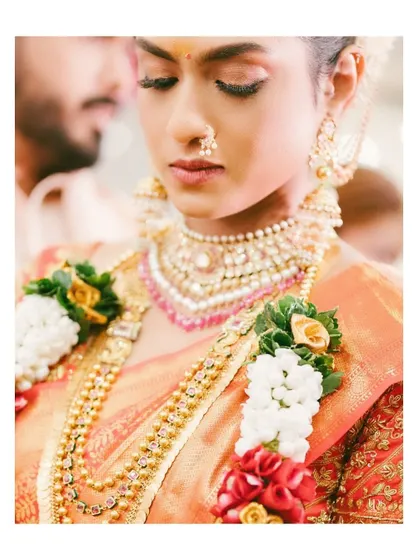 A close-up portrait of a beautiful South Indian bride, adorned in traditional gold jewelry. The focus is on the intricate details and her serene expression.