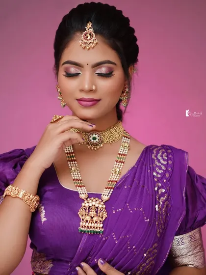 A model getting her makeup done for a shoot featuring our purple saree and blouse.
