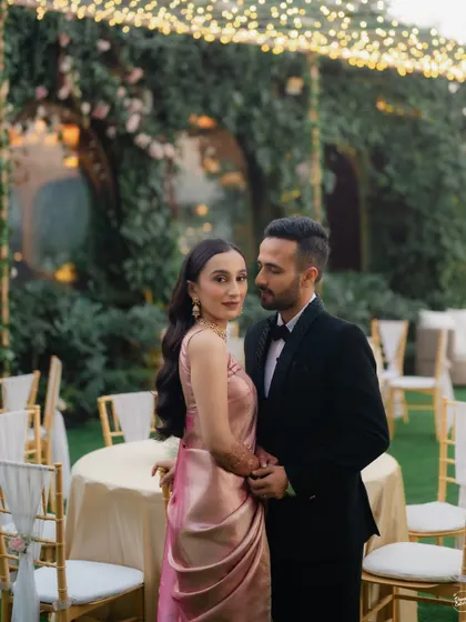 A full-length portrait showcasing the couple's elegant reception attire. The classic pose and beautiful garden setting at Gallops, Mumbai, make for a sophisticated and timeless wedding photograph.