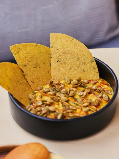 Our Sweet Corn Khichdi, topped with spiced pumpkin seeds and served with crispy methi thepla. It’s a comforting dish, perfect for delivery.