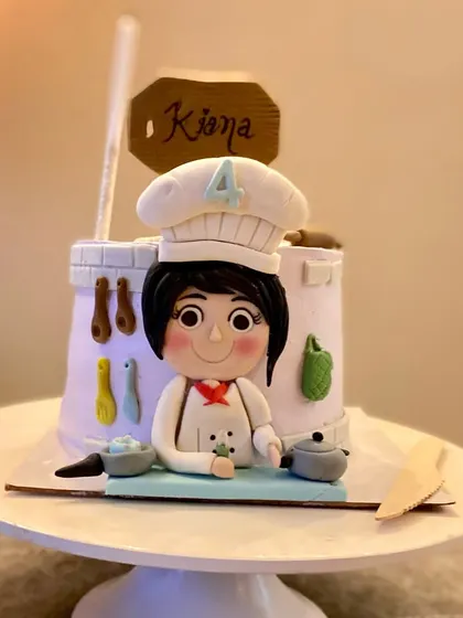 A wider shot of the adorable chef-themed cake, ready for its close-up.