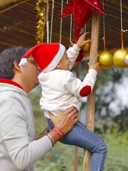 A father helps his child reach for a Christmas ornament hanging at one of our festive stalls.