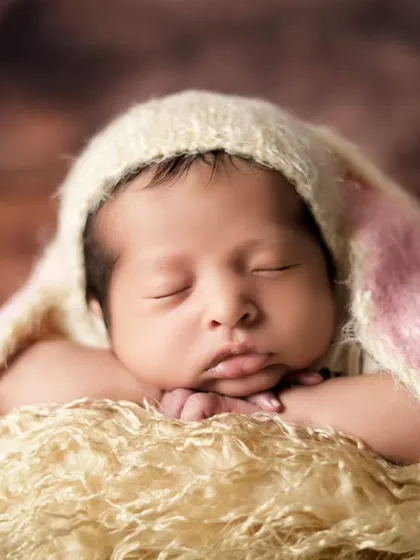 A close-up of the 'chin on hands' pose, one of the most classic and adorable newborn poses. It requires a lot of patience and skill to achieve safely.