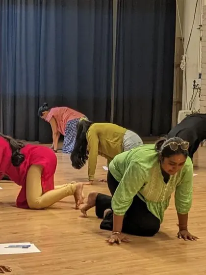 Participants in an intuitive movement workshop explore grounding and connection to the earth through animalistic crawling exercises.