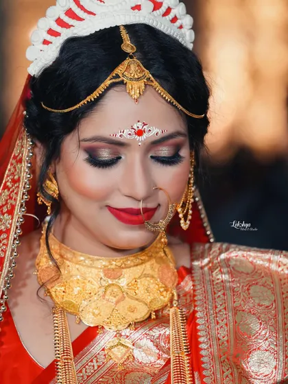 A beautiful close-up of the bride, showcasing her stunning eye makeup and traditional Bengali jewelry. Her serene expression radiates timeless elegance.