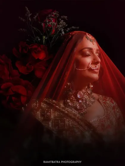A bride, veiled in red and surrounded by roses, closes her eyes in a moment of quiet contemplation. This artistic portrait is about capturing the soul of the moment, the emotions of the bride just before she begins her new chapter.