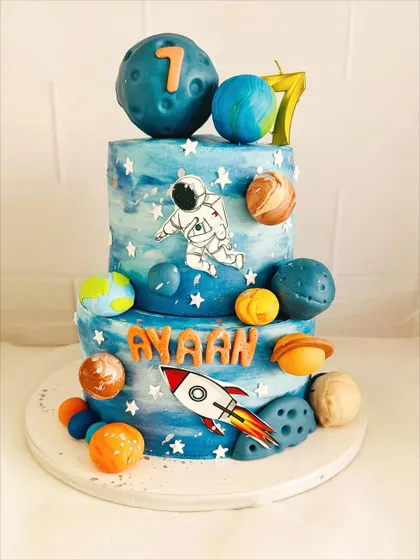 A two-tier galaxy cake with hand-painted watercolor effects and edible planets.