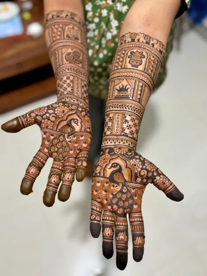 A wedding mehendi with beautiful peacock motifs on the palms and traditional symbols like Ganesha and a kalash on the arms.
