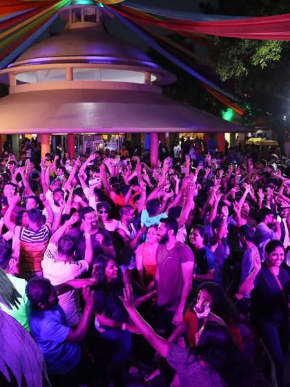 A photo of the massive, packed crowd at Wonderla, with their hands up, dancing under purple lights.
