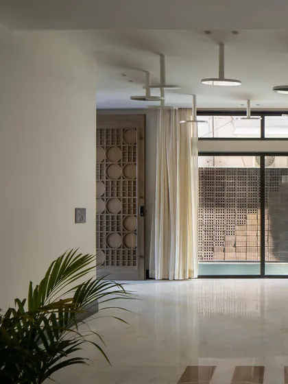A detail of the entrance foyer, with its custom carved wooden door and a view towards the water body. The space is designed to create a sense of tranquility upon arrival.