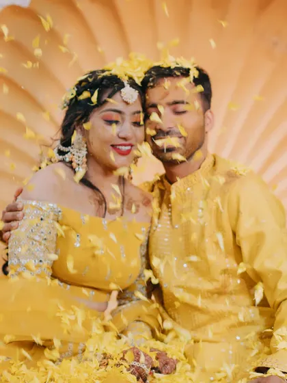 The couple enjoys a quiet moment together amidst a shower of yellow petals during their Haldi ceremony.