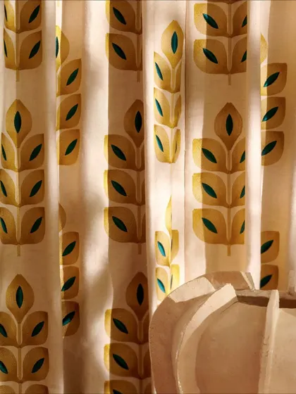 A close-up of an embroidered fabric from Élitis. The stylized leaf pattern, rendered in warm yellow and deep teal on a matte linen canvas, combines subtle texture with a timeless, expressive design.