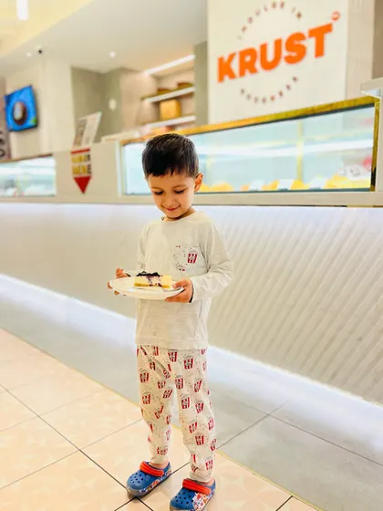 The same joyful moment, capturing the pure delight of a child with his favourite cheesecake. We are a family-friendly space where everyone can enjoy a sweet treat.