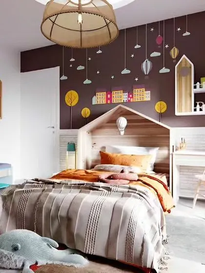 A playful and imaginative kid's bedroom with a house-shaped headboard and colorful wall decals. The room includes a compact study desk and a unique wardrobe with house-shaped cutouts.
