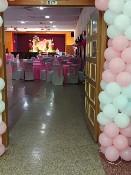 The entrance to the hall for the christening party, decorated with pink and white balloon pillars, giving guests a peek at the main stage inside.