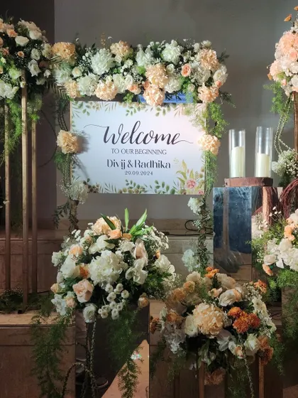 A personalized welcome sign for Divij and Radhika's Sangeet, surrounded by soft peach and white floral arrangements for a romantic and gentle feel.