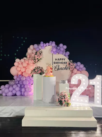 A view of the 21st birthday setup at night, showing how the light-up marquee numbers become a key feature of the decor. The backdrop and balloons are illuminated to create a beautiful evening ambiance.