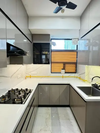 This U-shaped modular kitchen showcases glossy grey cabinets, a white marble-patterned backsplash, and smart use of space for a highly functional and stylish cooking area.