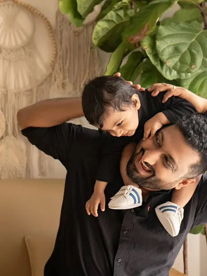 A father gives his son a shoulder ride in the studio. The son's happy expression and the dad's loving smile make this a classic and joyful shot.