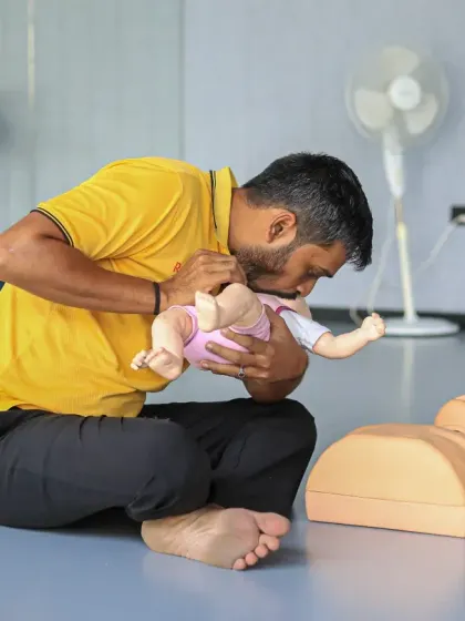 A trainer demonstrates the correct technique for infant CPR on a specialized manikin, a critical skill for coaches working with all age groups.