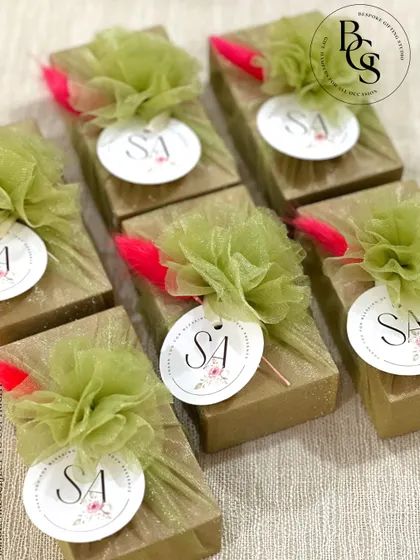 These small gift boxes are wrapped in gold glitter paper and topped with a green tulle pom-pom and a personalized initial tag. They are perfect as festive favours or for a glamorous party.